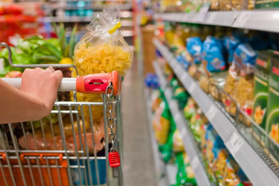 hand pushing a cart down a supermarket aisle